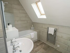 A modern bathroom with a freestanding bathtub, a white sink with multiple faucets, and a towel rack.