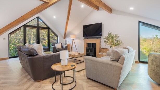 A spacious loft with high ceilings, large windows, a fireplace, and modern furniture. - Kolbeh (Ulverston)
