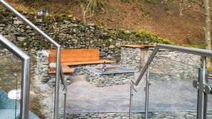 A stone staircase leading to a seating area with a stone wall backdrop. - Kolbeh (Ulverston)