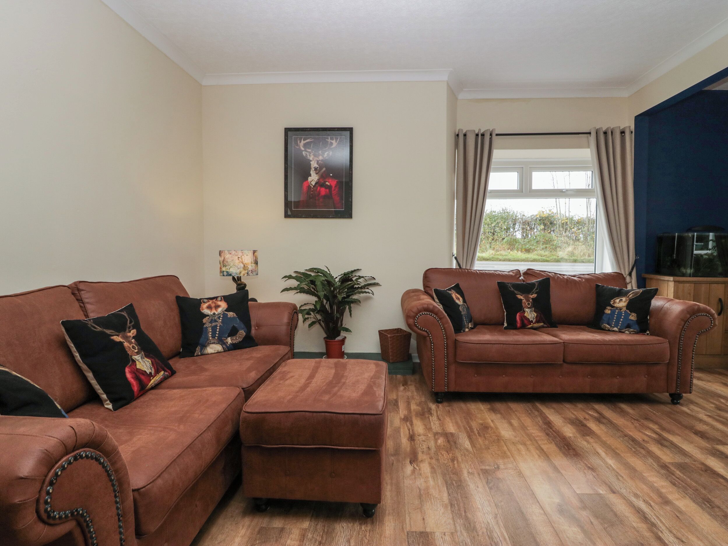 A living room with two brown leather sofas, a wooden coffee table, a potted plant, and a framed picture on the wall.