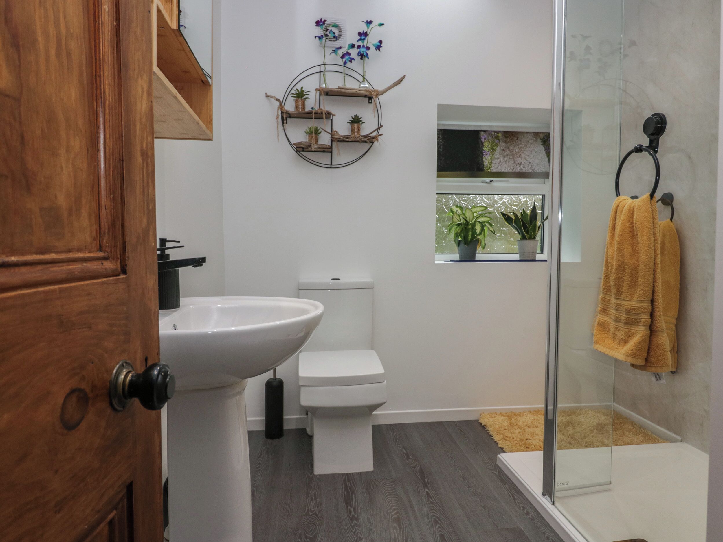 A bathroom with a white sink, toilet, and glass shower enclosure.