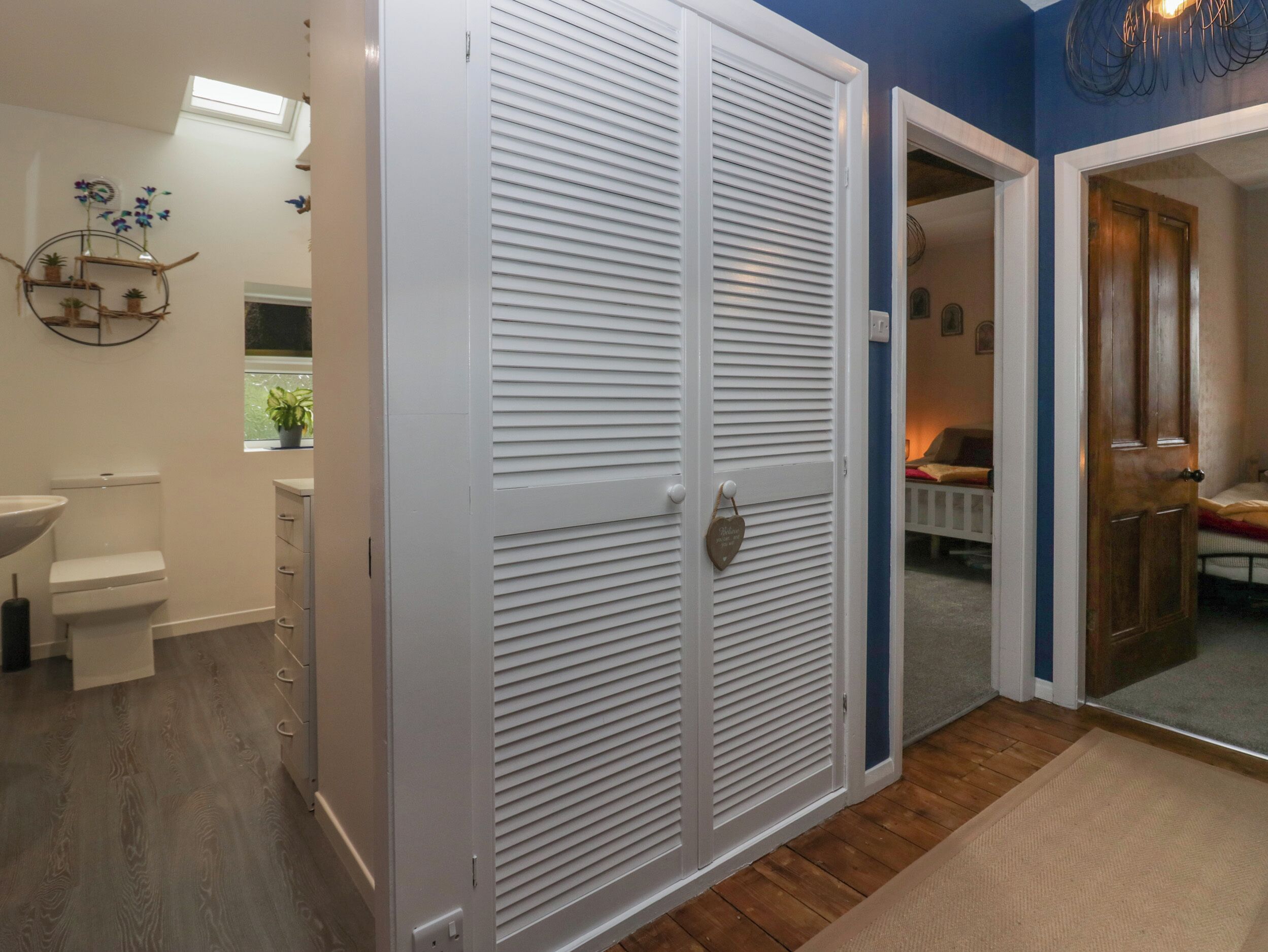 A bathroom with a toilet, sink, and storage cabinet.