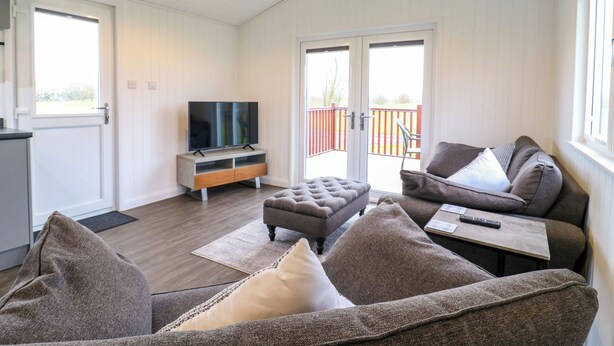 A cozy living room with a TV, sofas, and a dining table.