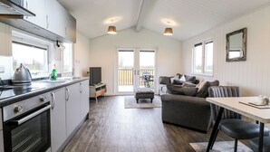 A modern kitchen with a built-in oven, a dining area with a table and chairs, and a cozy living space with a sofa and a TV.
