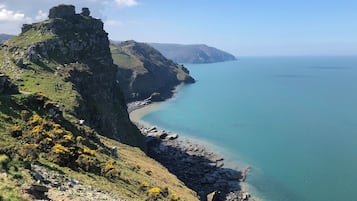 Un paysage côtier avec une falaise rocheuse, une mer bleue et limpide, et une vue lointaine sur l’horizon.
