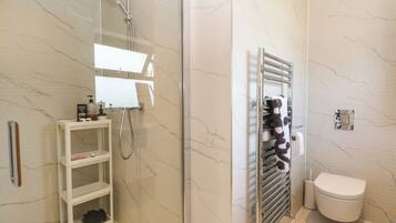 Un baño moderno con ducha de vidrio, inodoro blanco y perchero para toallas.