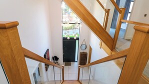 Una escalera de madera con barandillas de vidrio que da a un espacio exterior.