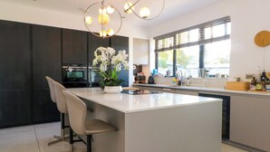 Una cocina moderna con una isla central, armarios oscuros y un ventanal grande.