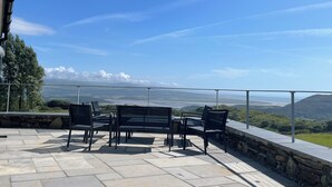 A terrace with a view of a coastal landscape, stone flooring, and black metal furniture. - Beudy Mawr (Garndolbenmaen)