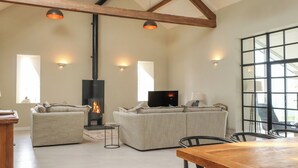 A spacious living room with a fireplace, two sofas, a TV, and a dining table. - Beudy Mawr (Garndolbenmaen)