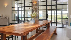 A wooden dining table with benches, a vase with flowers, and a stone wall. - Beudy Mawr (Garndolbenmaen)