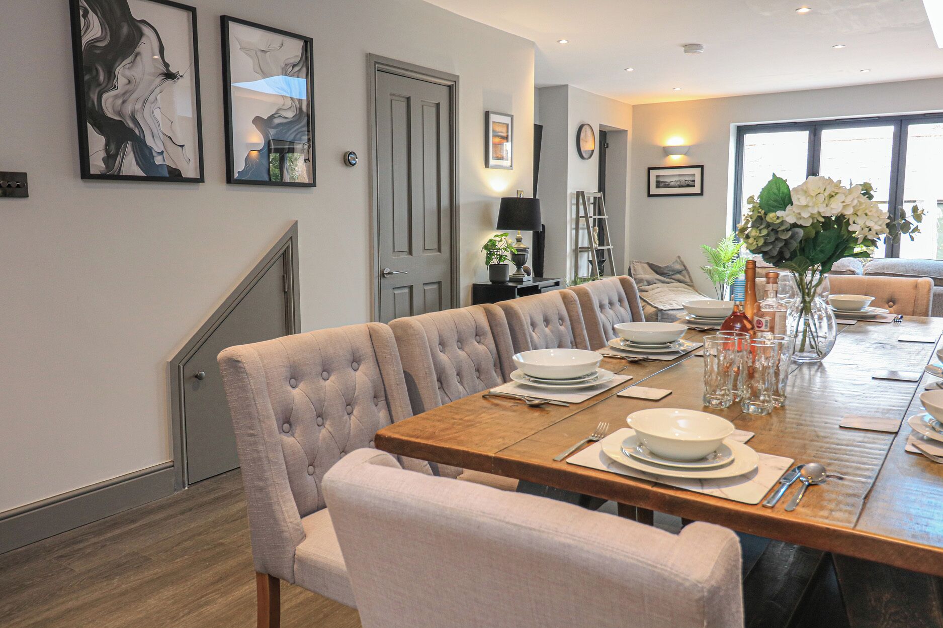 A dining area with a wooden table set for four, surrounded by cushioned chairs.