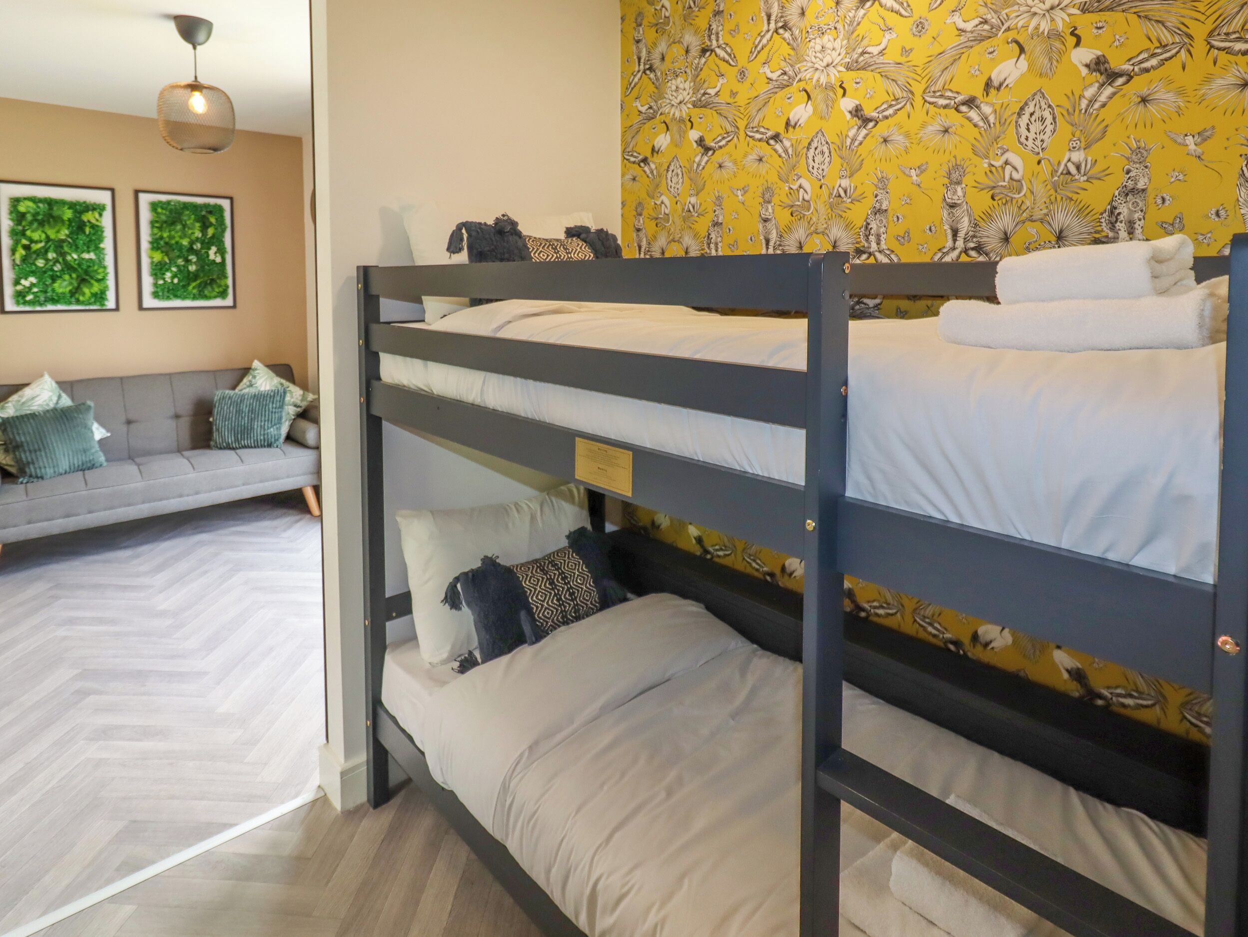 A bunk bed room with a sofa and two framed pictures on the wall.