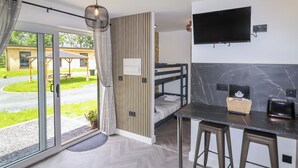 Ein modernes Zimmer mit Bett, Schreibtisch, Fernseher und Blick ins Freie.
