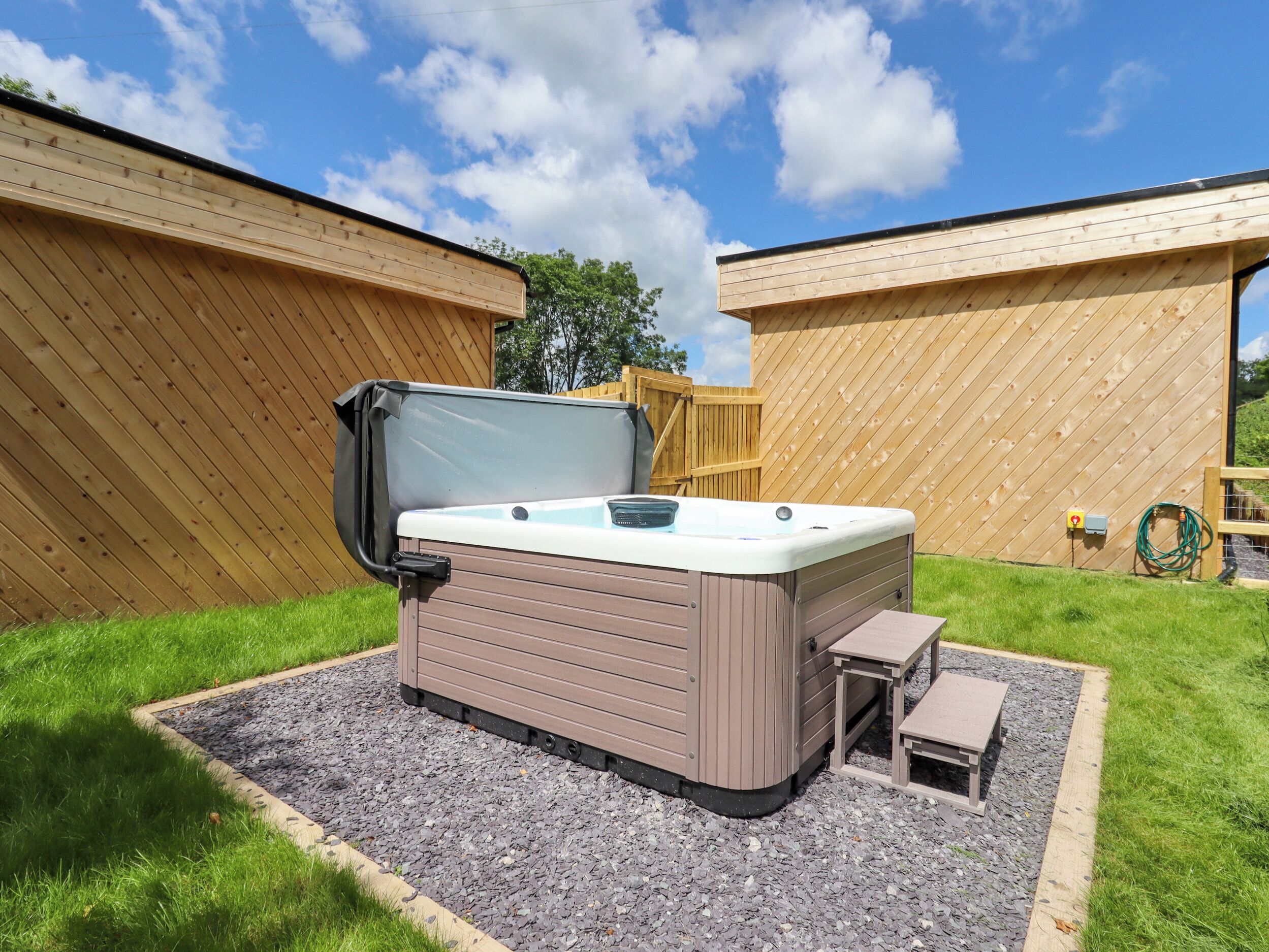 A hot tub with a table and bench, surrounded by a wooden fence and gravel.