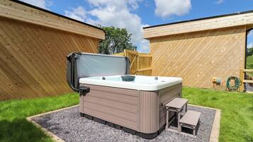 A hot tub with a table and bench, surrounded by a wooden fence and gravel.