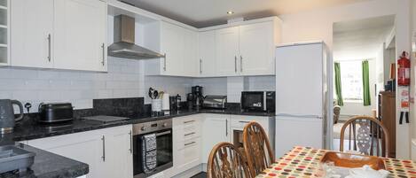 A modern kitchen with white cabinets, a black countertop, and a dining area with a polka dot tablecloth.