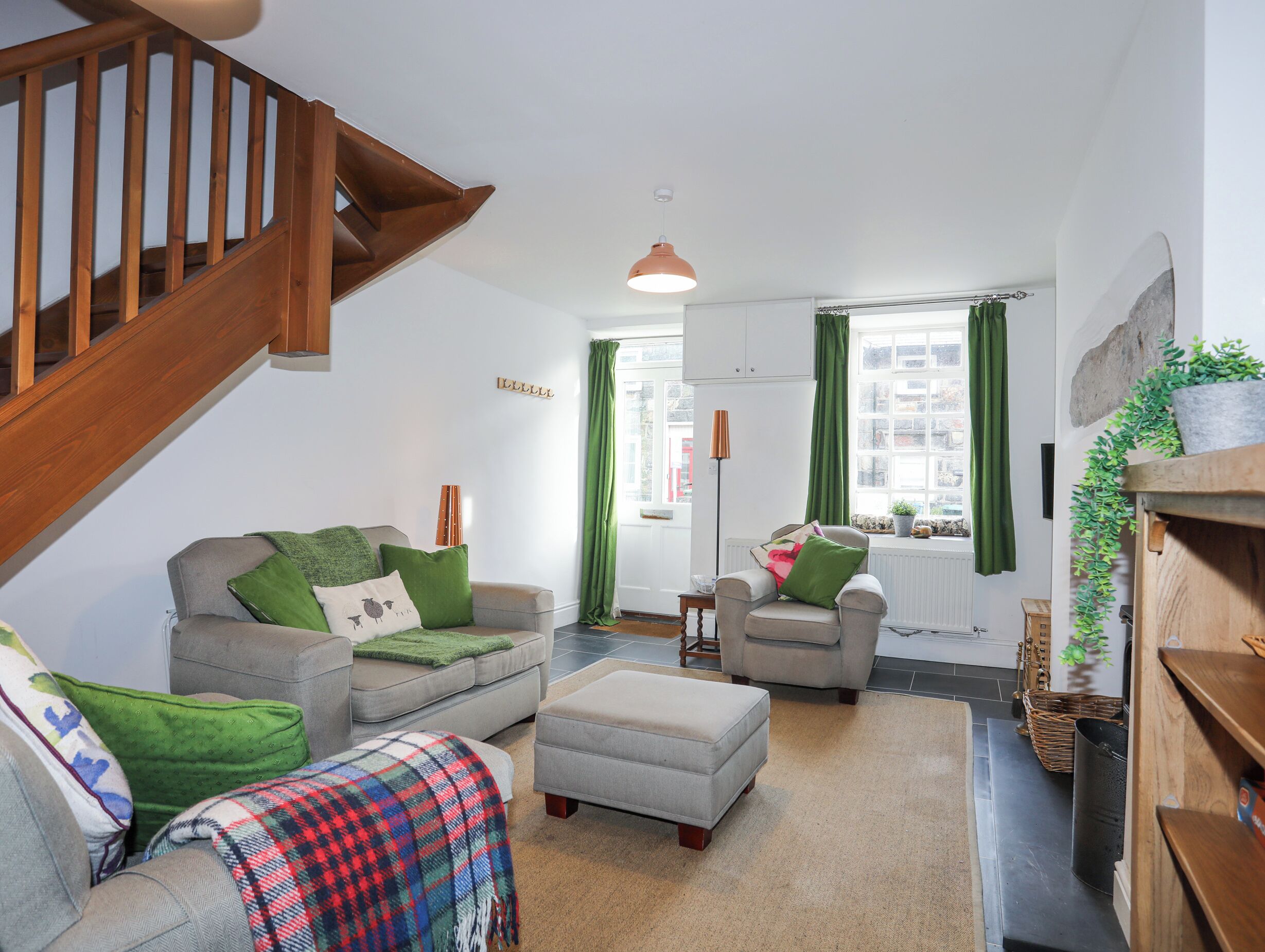 A living room with a staircase, a sofa set, a chair, a small table, and a radiator.