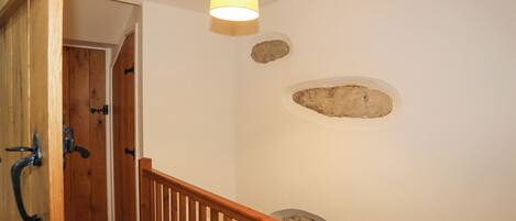 A wooden staircase with a railing, a hanging light fixture, and a door with a metal handle.