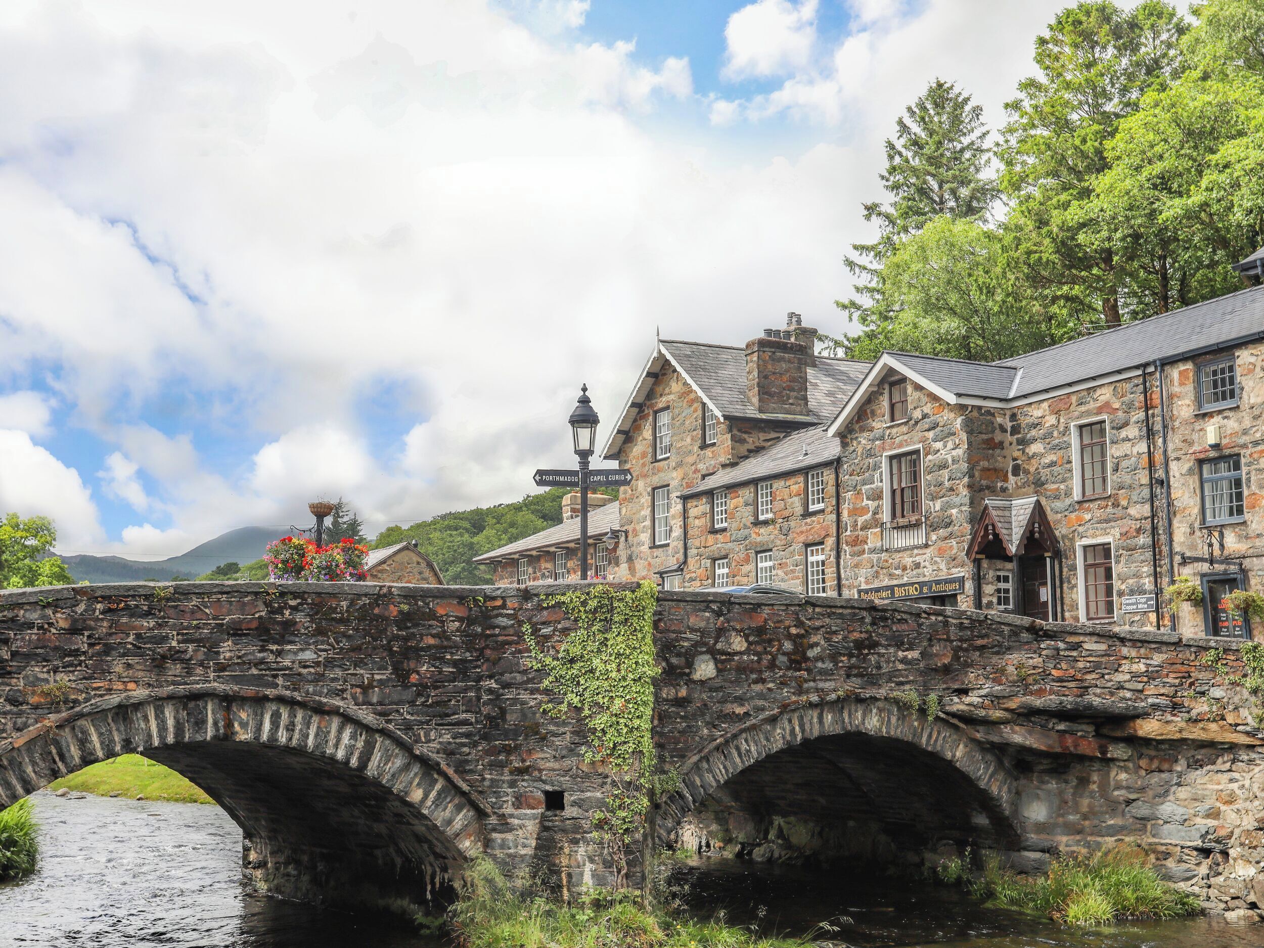 A stone bridge over a river with a stone building on the right.