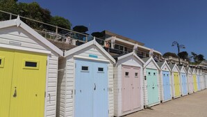 Een rij kleurrijke strandhutten met een balkon en een bordje met de tekst 'Bella Beach'.