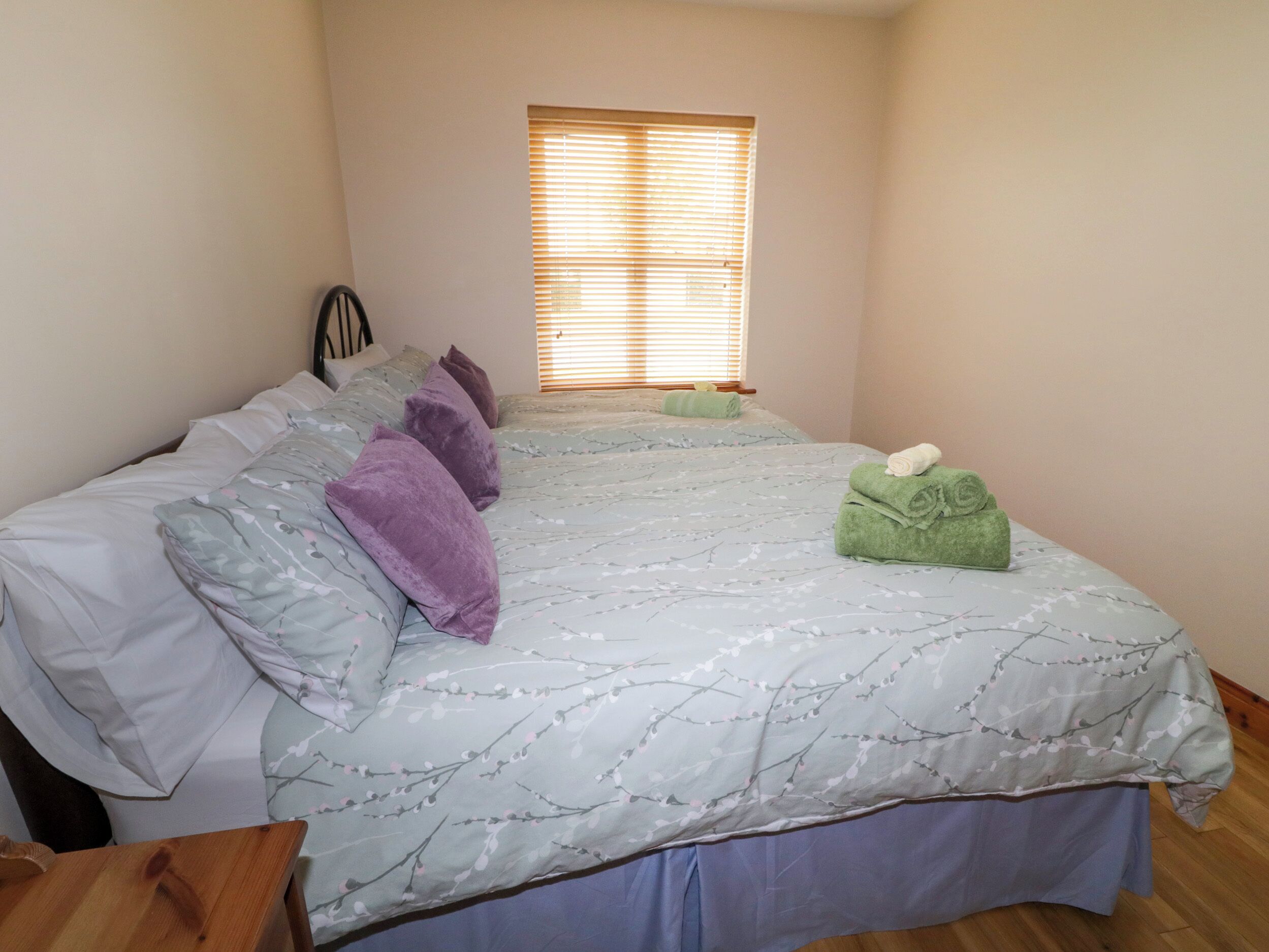 Un dormitorio con dos camas, una ventana con persianas y suelo de madera.