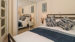 Une chambre à coucher avec un lit, des tables de chevet, un miroir et un tableau encadré au mur.