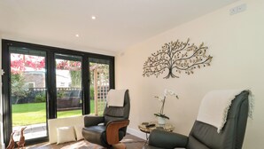 Un salon moderne avec deux fauteuils en cuir, une table basse en verre et une décoration murale représentant un arbre en métal.