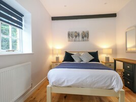A bedroom with a bed, bedside lamps, a dresser, a radiator, and a window with blinds.