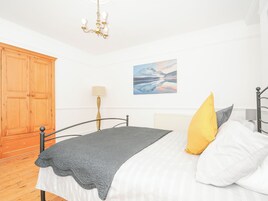 Quarto com uma cama, um guarda-roupa de madeira, um quadro e um candelabro.