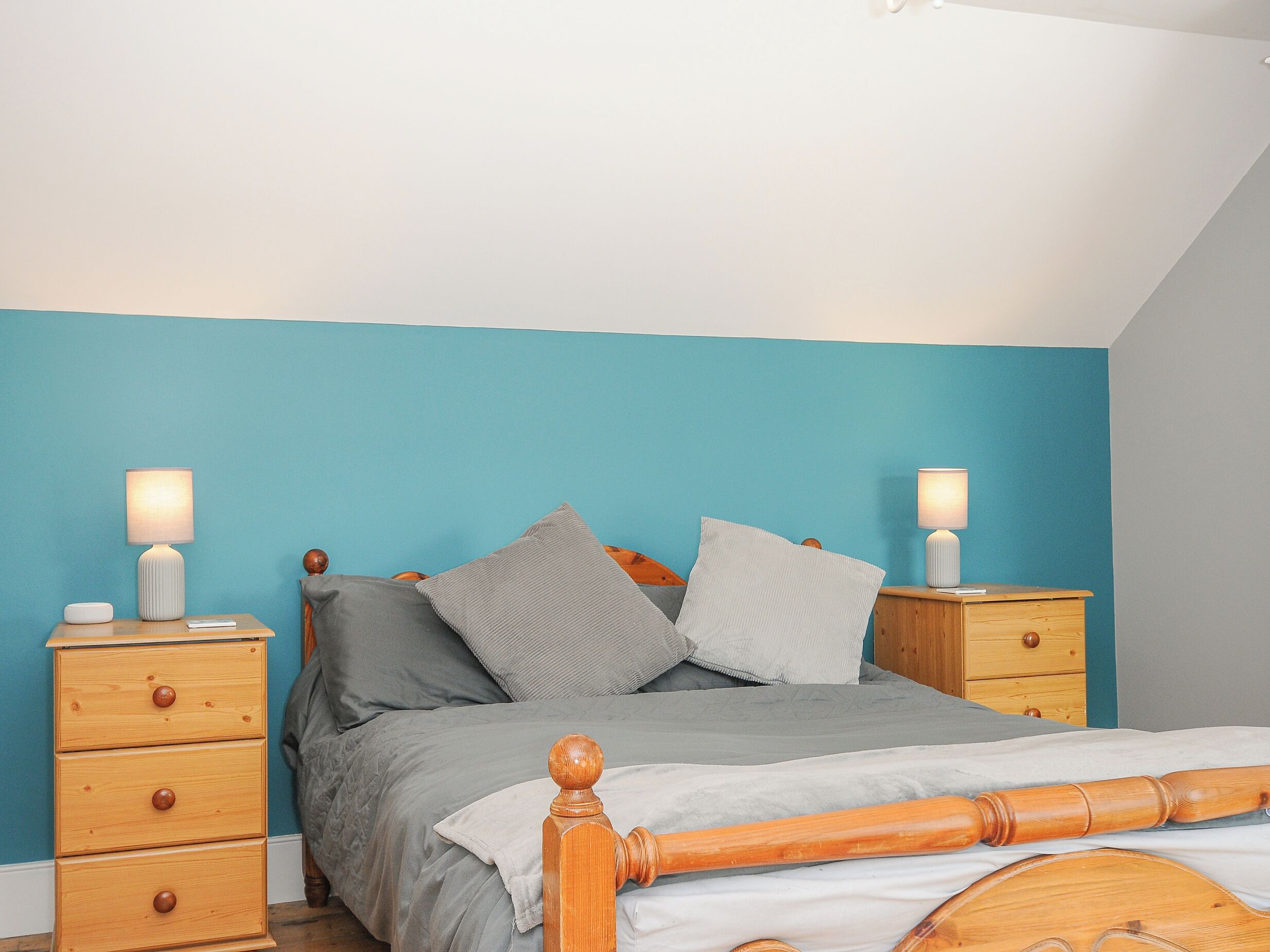 A bedroom with a bed, two nightstands, and a wooden dresser.