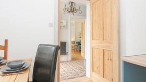 A dining area with a wooden table, a black chair, and a chandelier. - Albert House (Looe)
