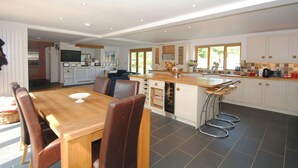 Een ruime keuken met een eetgedeelte, met een houten tafel, stoelen en een inbouwoven.