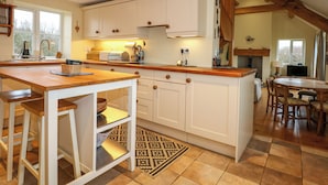 A kitchen with white cabinetry, a wooden countertop, and a patterned rug. - Tan Y Ffordd (Pwllheli)