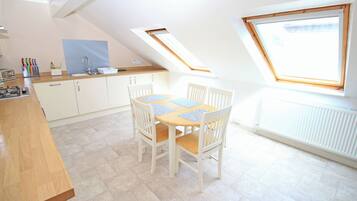 A kitchen with a dining table, chairs, a window, and a skylight.