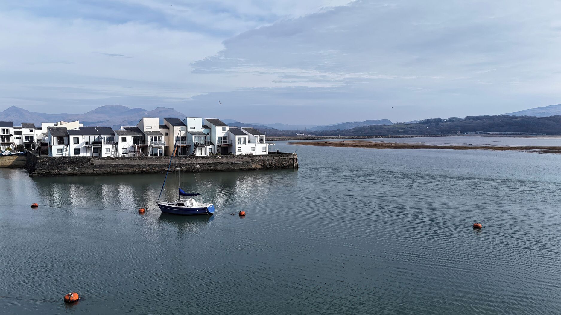 Un ensemble de bâtiments situé sur la côte, comprenant un port de plaisance, des bateaux et une mer calme.