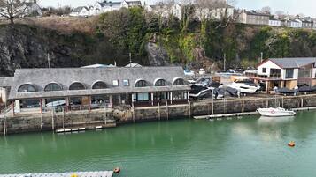 A coastal building with a stone facade, multiple arched windows, and a dock area with boats.