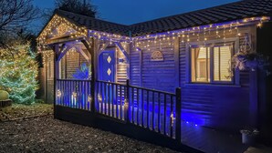 Une maison avec un porche, décorée de guirlandes lumineuses et d’un sapin de Noël.