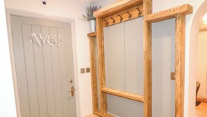 Une porte ornée d’un monogramme décoratif et un miroir à cadre en bois, accompagné d’un banc.