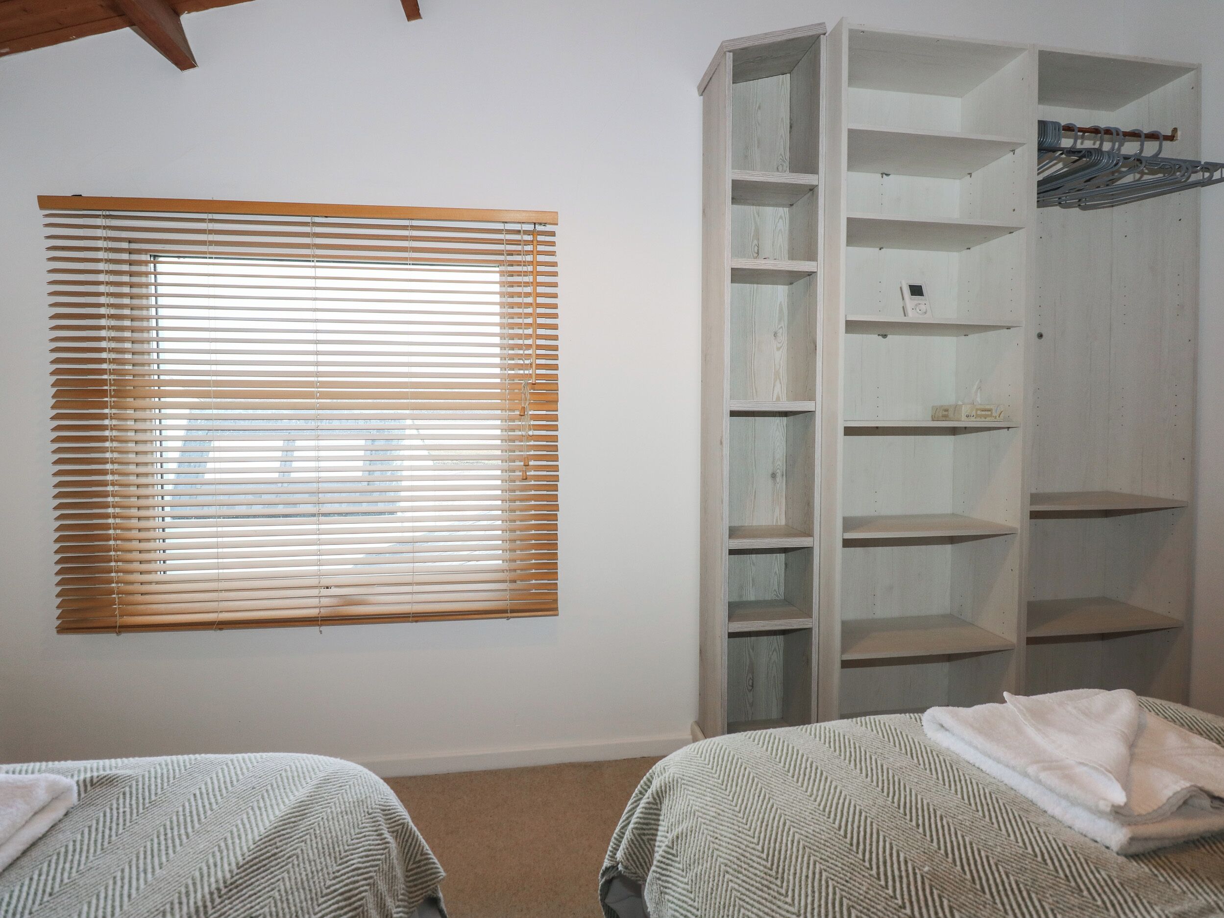 Un dormitorio con dos camas, una ventana con persianas y un armario de madera.