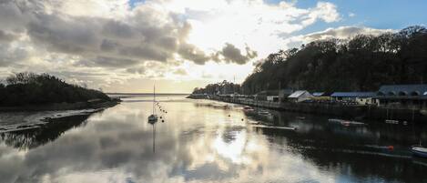 A calm river with boats, a dock, and a bridge in the background.
