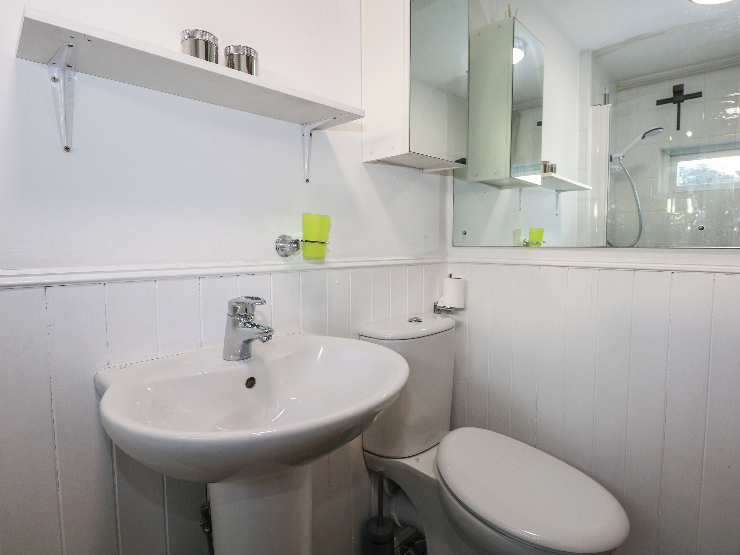 A bathroom with a white sink, toilet, and a mirror above the sink.