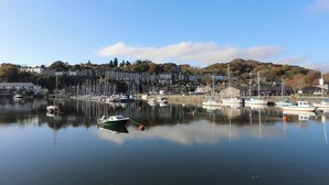 A marina with boats docked, calm water, and buildings in the background.