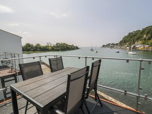 A deck with a table and chairs overlooking a calm body of water with boats. - Seafarer's Haven (Porthmadog)