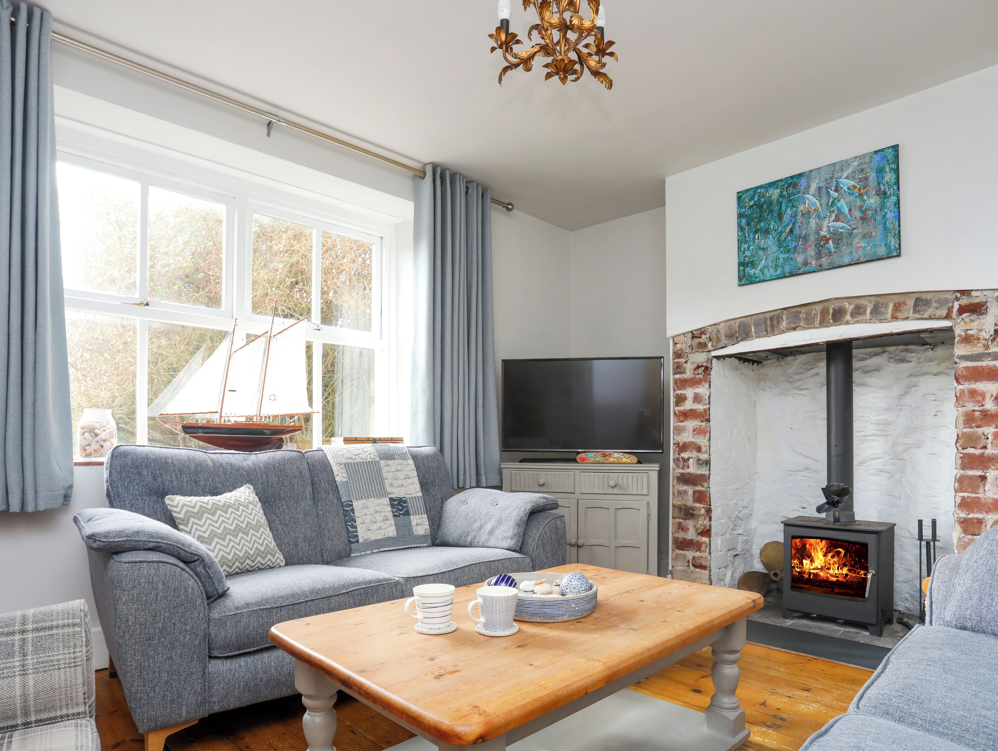 A cozy living room with a fireplace, a sofa, a TV, and a wooden coffee table.