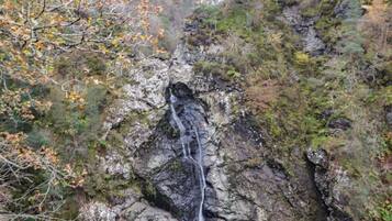 Une cascade se déversant le long d’une falaise rocheuse, entourée d’arbres.