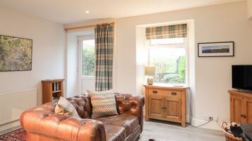 A cozy living room with a leather sofa, wooden cabinet, and a television.
