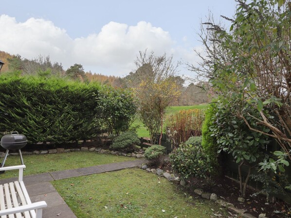 A garden with a barbecue grill, a wooden bench, and various plants. - Wendy's Place (Inverness)