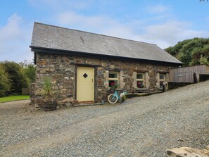 A stone building with a sloped roof, a single entrance door, and a bicycle parked outside. - Seaforest Lodge (Gorey)