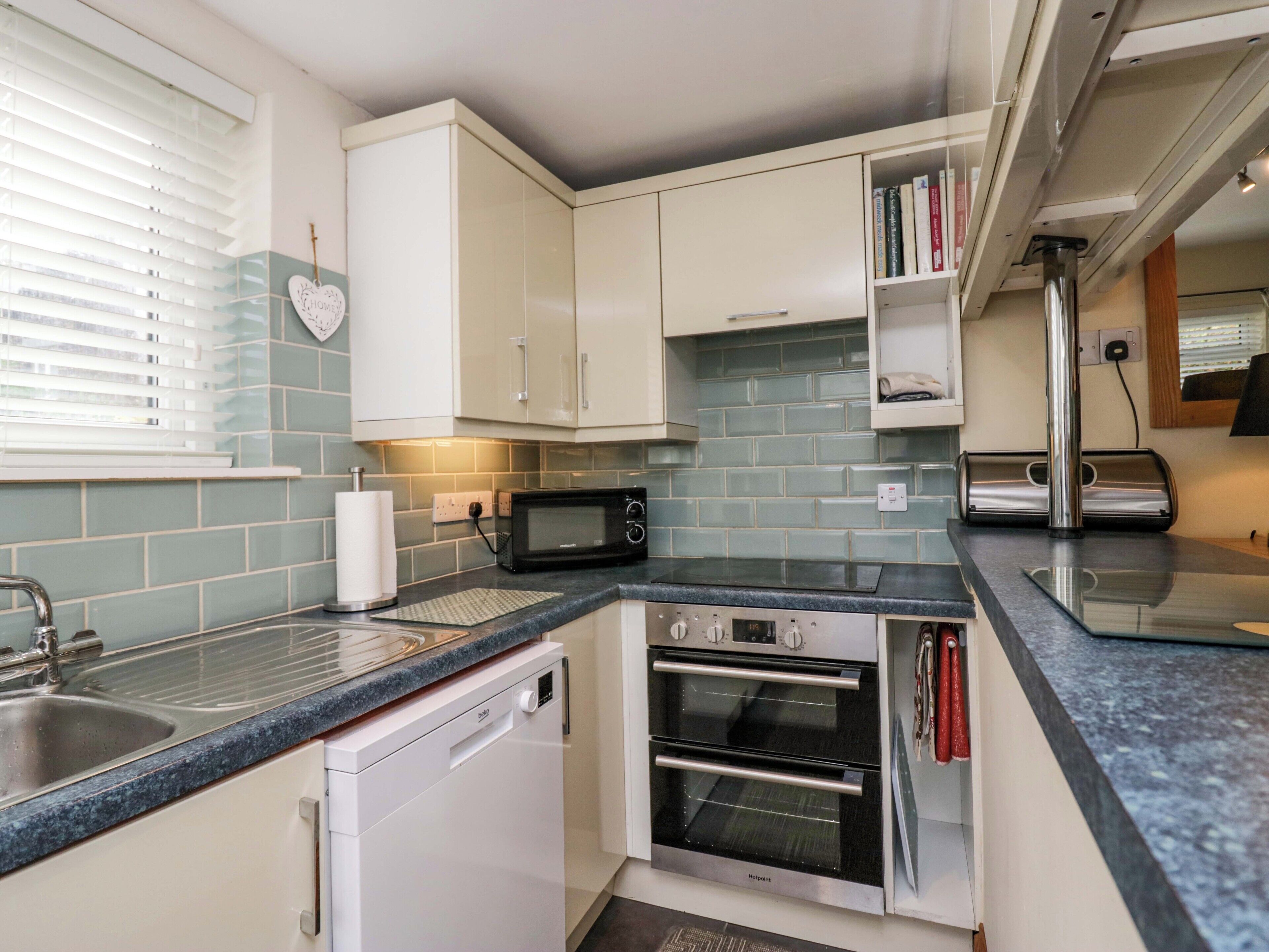 A compact kitchen with white cabinets, a microwave, an oven, and a dishwasher.